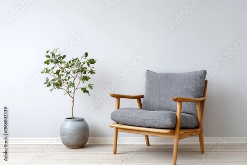 A modern wooden armchair with a potted plant sits against a plain wall.