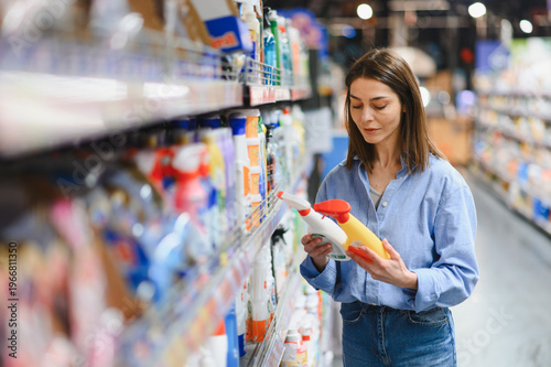 Fotografi Woman choosing cleaning products at supermarket aisle