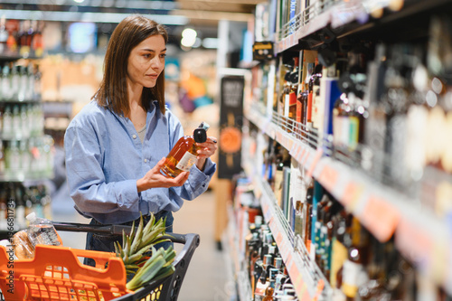 Woman shopping for spirits in supermarket aisle