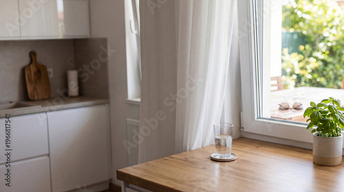 Refreshing glass of water and basil plant on kitchen counter, natural light, healthy, tranquil home.