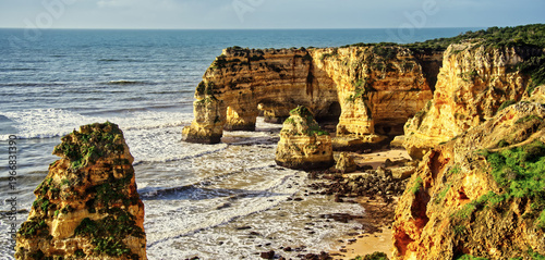 Algarve coastline featuring marinha beach rock formations and natural arches, ocean waves washing onto the sandy shore
