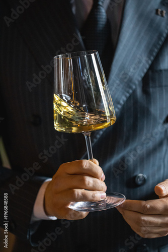 Sommelier swirling white wine in glass to release aroma in elegant tasting setting closeup