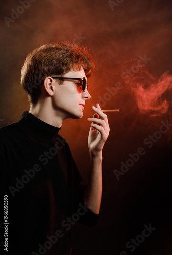 Cinematic side profile of male model with sunglasses and cigarette smoke.