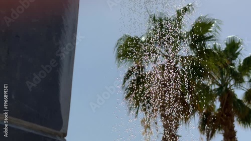Vibrant Tropical Scene. Glistening Drops Cascade Over Lush Palm Leaves Under Bright Sky