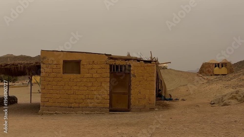 Isolated Adobe Structure With Simple Roof And Open Entrance Amidst Gentle Foothills And Warm Colors