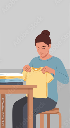 A woman sitting at a table folding a stack of clean laundry in her home space
