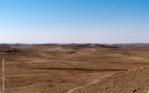 Fotografie A vast, desolate landscape with dry soil and no vegetation, blue sky, brown earth