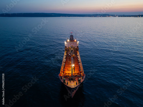 Aerial View of Industrial Tanker Ship at Sea During Sunset with City Lights