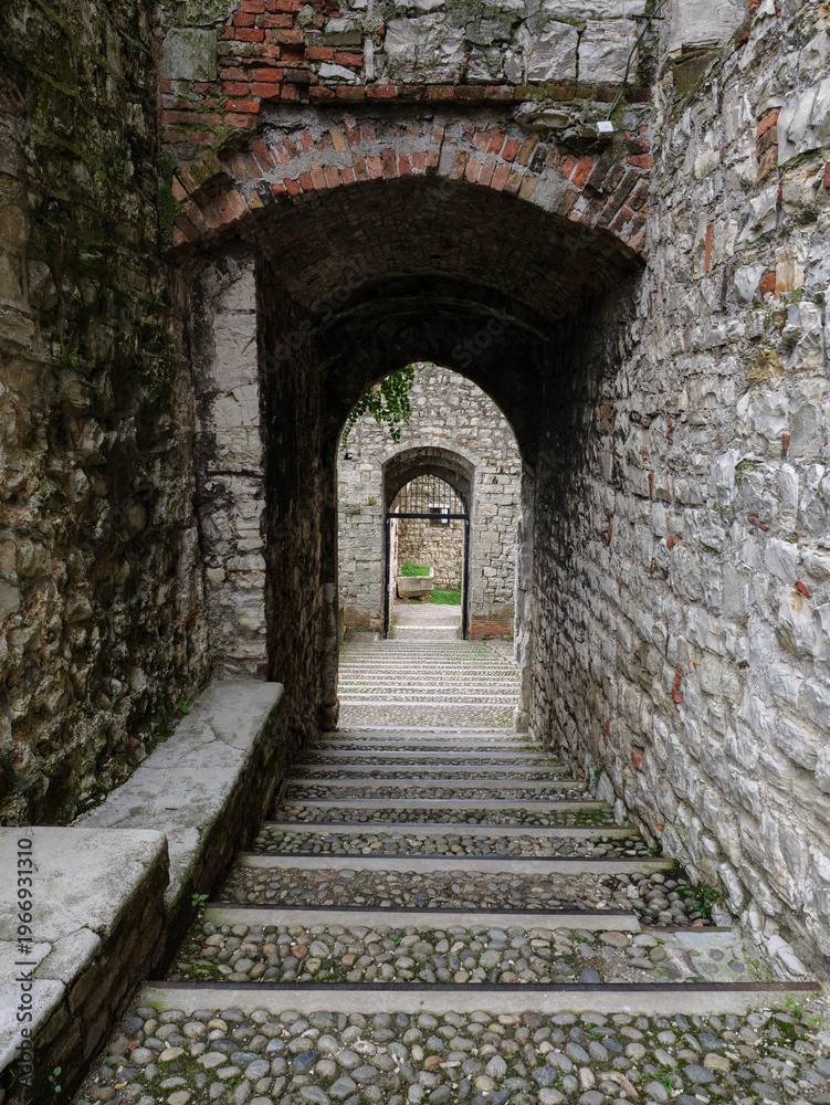 Obraz premium Stone Cobblestone Steps Under Successive Brick Arches In A Narrow Medieval Fortification Passage, Brescia, Italy