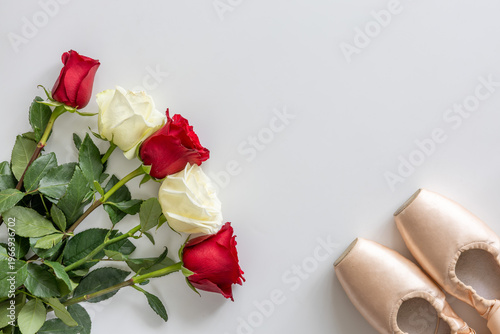 Ballet shoes with red and white roses bouquet on white background. Top view, flat lay, copy space