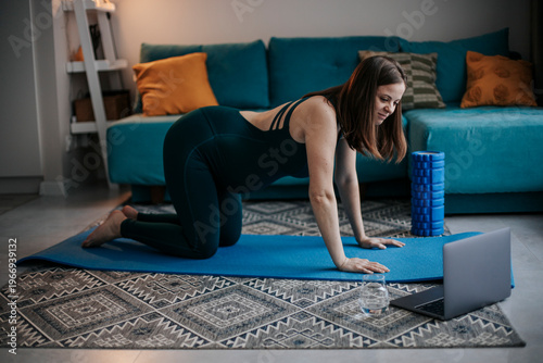 Prenatal yoga exercise with laptop in living room for back pain relief