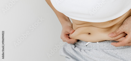 Close-Up of Woman's Hands Pinching Belly Fat Skin Fold at Waist in White Crop Top and Gray skirt — Female Checking Abdominal Subcutaneous Fat, Body Weight Awareness, Healthy Lifestyle Motivation