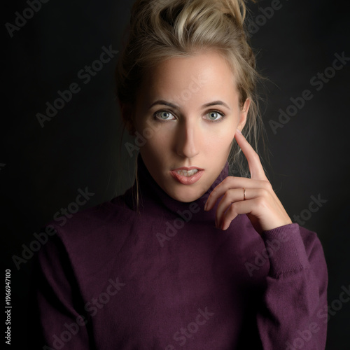 Elegant portrait of thoughtful woman in purple sweater with soft dramatic lighting.