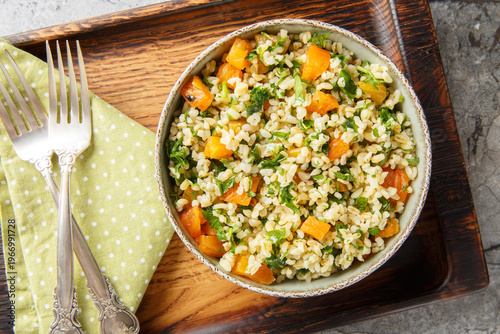 Fotografie Low-calorie dietary bulgur with parsley and dried apricots close-up in a bowl on the table