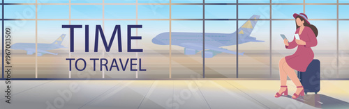 A stylish woman waiting at the airport terminal, checking her smartphone while sitting with luggage near a large panoramic window with airplanes outside. Travel and departure concept with copy space.