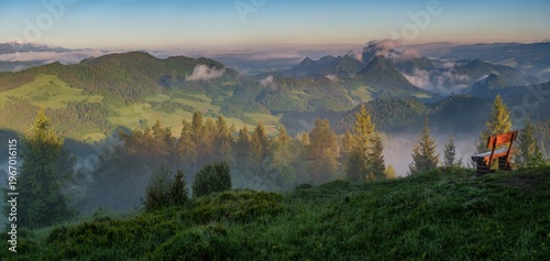 Beautiful sunrise landscape in Pieniny mountains with wooden bench overlooking misty valleys and iconic Tri Koruny peaks on the Poland Slovakia border. Ideal for travel and nature themes.