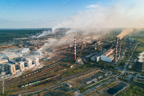 Industrial pollution causes environmental degradation in a large manufacturing facility with smoke and emissions during daytime
