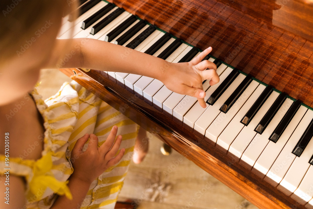 Fototapeta premium Cute child playing piano indoors learning music childhood education creativity talent and practice