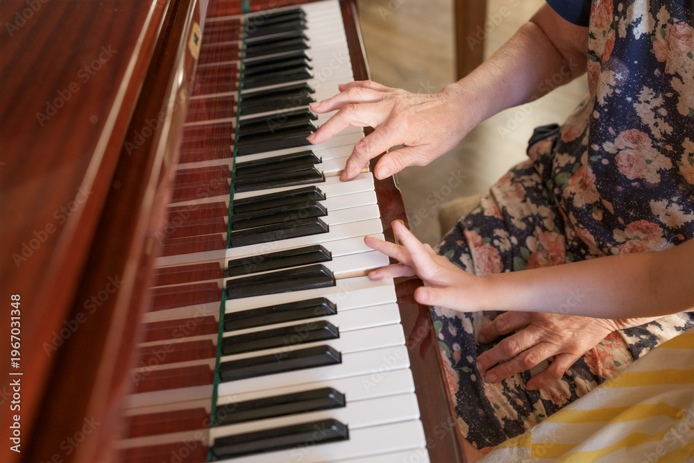 Fototapeta premium Senior woman guiding child piano practice at home music education family care and generational wisdom