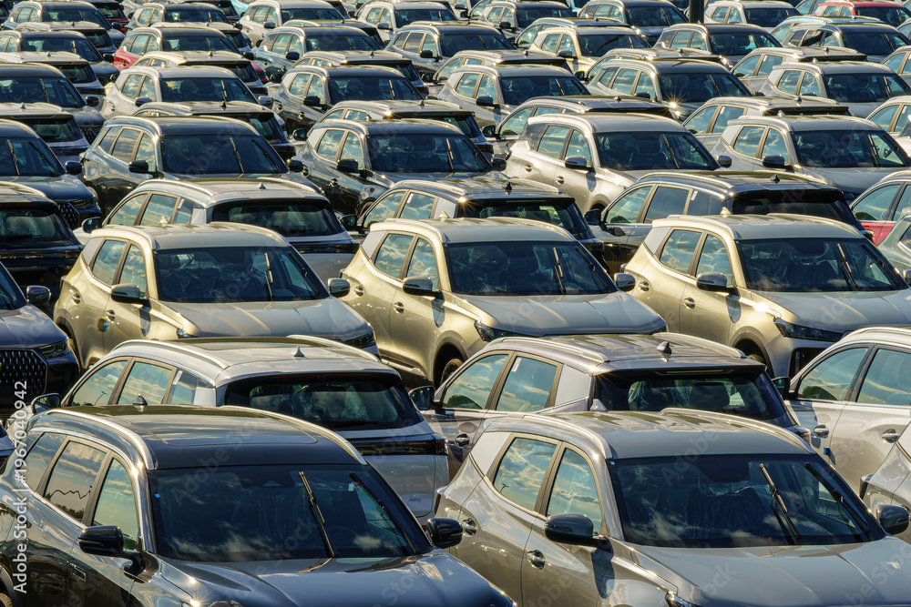 Fototapeta premium Russia, Kaluga, AGR Automotive Group - July 7, 2025: Rows of new cars parked close together in large open-air lot, representing automotive industry production and transportation