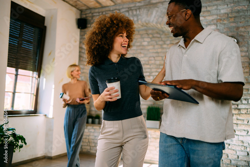 Tableau sur toile Smiling multi-ethnic colleagues engaging in conversation while walking in a mode