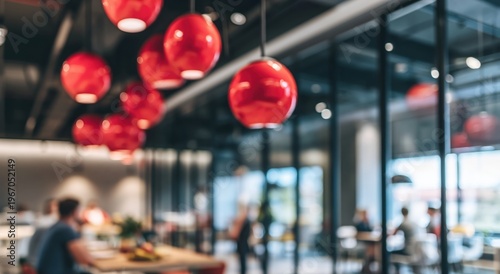 Modern interior with red pendant lights hanging from the ceiling, blurred background of people and glass walls, creating a vibrant and contemporary atmosphere.