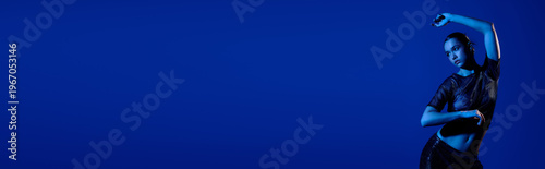 Photography Stylish young woman showcases trendy outfit against bold blue backdrop in studio