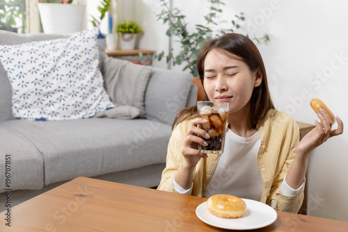 Asian women enjoying soda cola drink and donut, showing sweet food craving, indulgence and lifestyle choices with sugary snacks, diet, everyday eating habits.