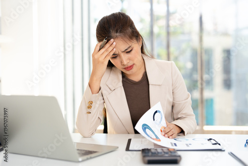 Asian businesswoman are serious at work causing headache stressed out with documents and laptop at the office.