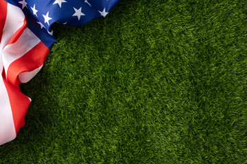 American flag lies on lush green grass evoking Independence Day, Memorial Day and Veterans Day themes with patriotic colors, fabric texture and outdoor summer celebration