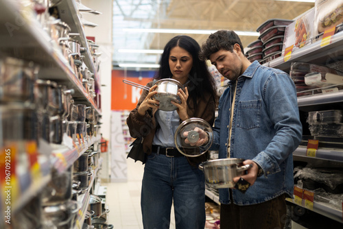 Fotografi Young couple comparing pots and pans and making a purchasing decision in a store