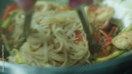 A cook stirs cooked noodles in a wok over a fire. Asian food. Cooking noodles. Stir-frying noodles with vegetables.
