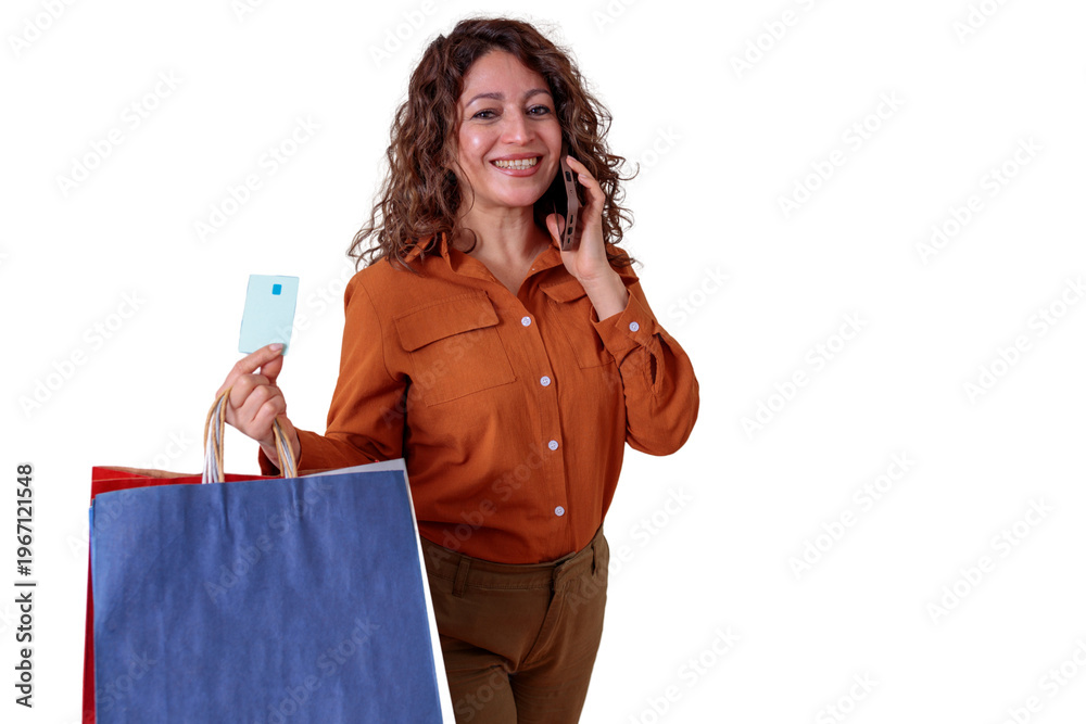 Naklejka premium Smiling woman enjoying retail therapy, multitasking with a phone call, holding shopping bags and a credit card. Transparent background