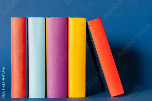 Фотография Five books with multi-colored spines on a dark blue background.