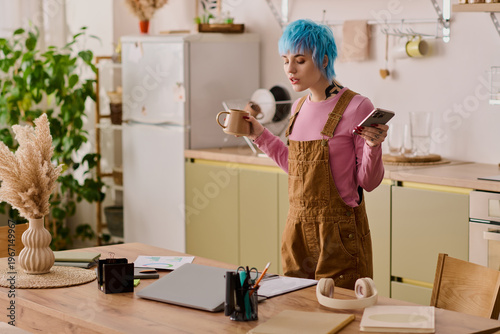 Fényképezés Young stylish woman enjoying her morning coffee while multitasking in a cozy kit