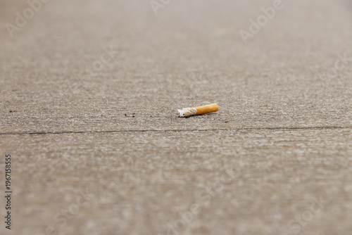 Tableau sur toile Cigarette butt thrown on concrete floor of the pavement in urban city shows bad habit in environment pollution and risk danger for people health