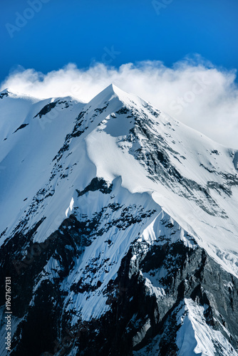 Snowy Annapurna peak with sharp ridge and clouds, Himalayan mountain Nepal