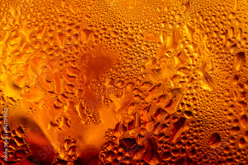 Macro view of the surface of a cola drink; a close-up image of a refreshing iced tea with water droplets clinging to the glass,Macro shot of a cold amber beverage, likely iced tea or soda, showing.