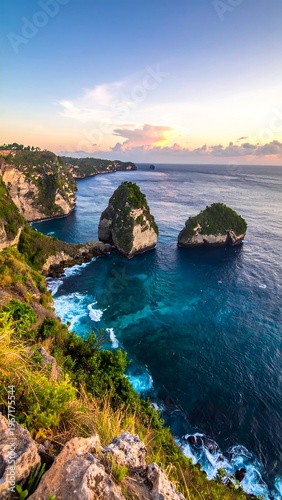Vertical image of a rocky coast with turquoise waters under a blue and orange sky