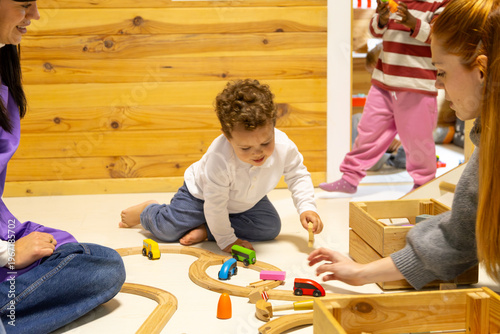 Toddler playing with wooden toy train set in kindergarten