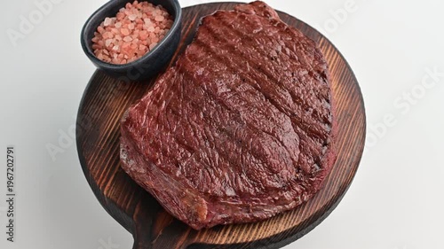 Cooked meat served on a wooden platter with a side of salt in a clean setting