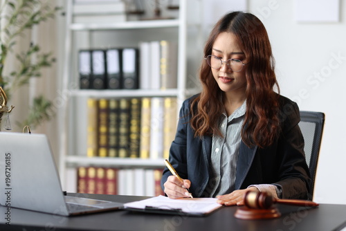 Female lawyer reviewing and signing a legal document while working on a case in her office.