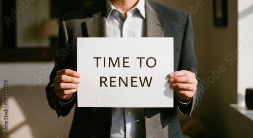 Man holding a sign that says Time to Renew in a business setting.