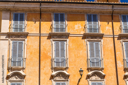 Italy Rome street orange house facade. Old historical building architecture in the city center. Italian windows with close shutters