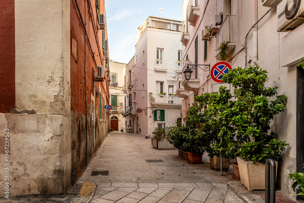 Fototapeta premium Charming narrow street decorated with flowers of picturesque Monopoli old town, Puglia, Italy