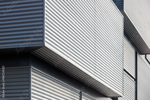 Photos Architectural facade with gray cladding corrugated metal panels of industrial or commercial building, contemporary architecture with vertical relief and material contrast