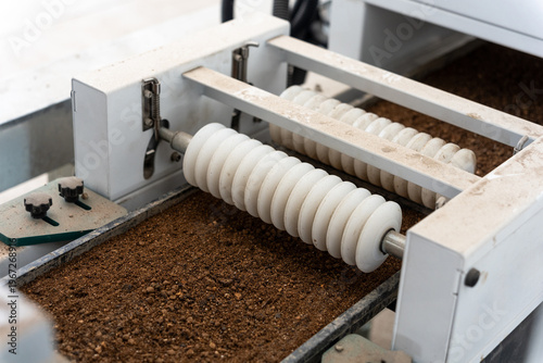 Industrial equipment with roller conveyor transporting coffee grounds material