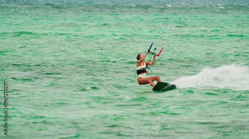 Sports woman kitesurfing in ocean in white bikini. Extreme summer sports
