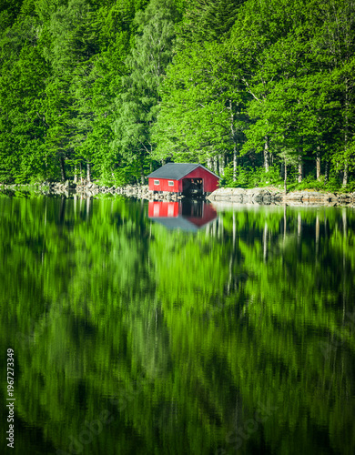 Red boathouse on the shore of a lake in Norway