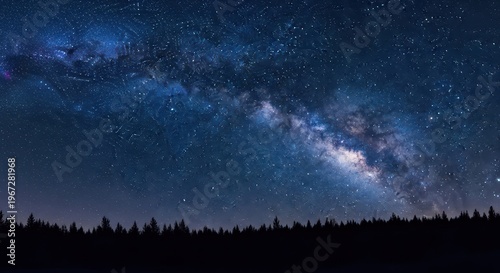 Stunning panoramic view of the milky way galaxy stretching across the night sky above a dark silhouette of a pine forest in a serene wilderness